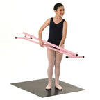 Young dancer holding a pink ballet barre on a white background