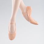 Ballet shoes worn by a person on a light gray background