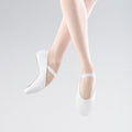 White ballet shoes worn with sheer white stockings on a light gray background