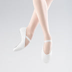 White ballet shoes worn with sheer white stockings on a light gray background