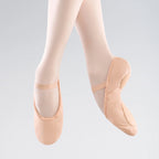 Ballet shoes worn with beige tights on a light gray background