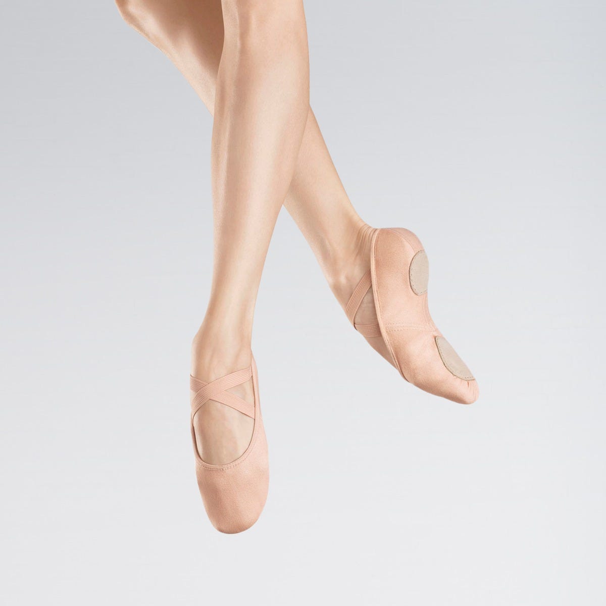 Ballet shoes worn on a plain background