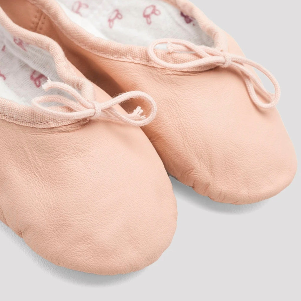 Pair of pink ballet shoes with ribbons on a light gray background