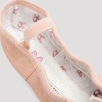 Close-up of a pink ballet shoe with white lining featuring red and pink floral patterns on a light gray background.