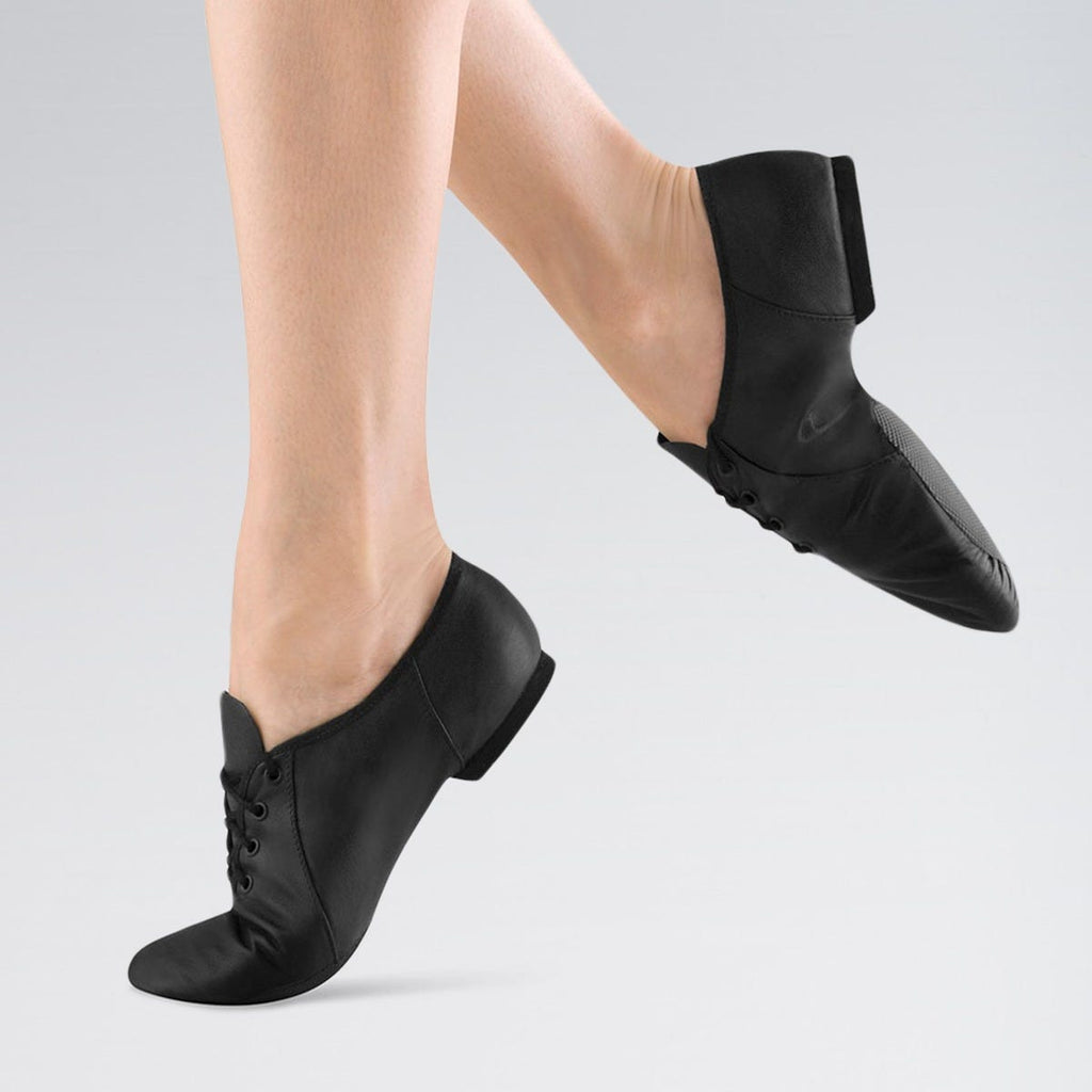 Black jazz shoes worn by a person on a light grey background