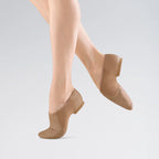 Beige dance shoes worn by a person on a light gray background