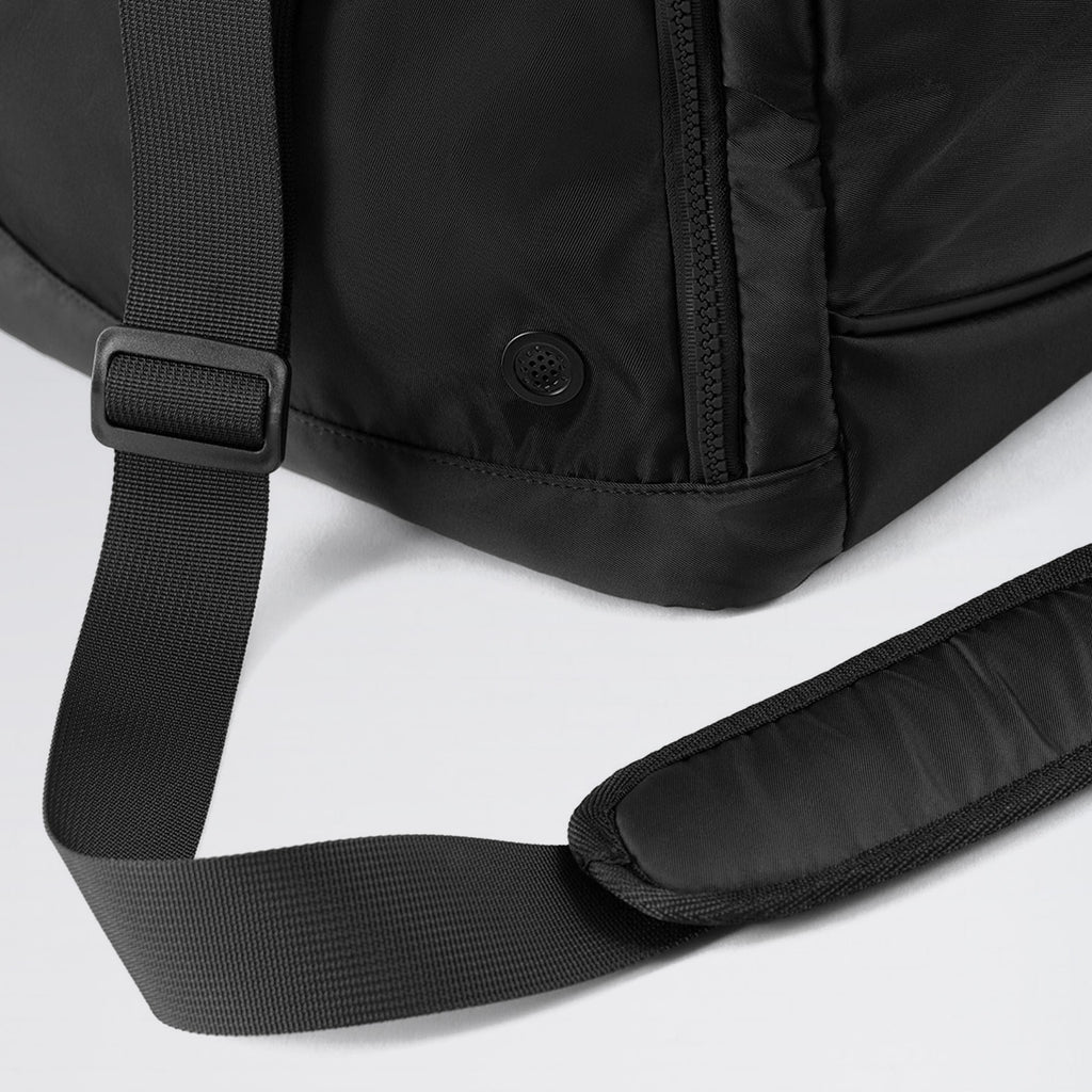 Close-up of a black backpack with a strap on a light gray background