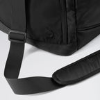 Close-up of a black backpack with a strap on a light gray background