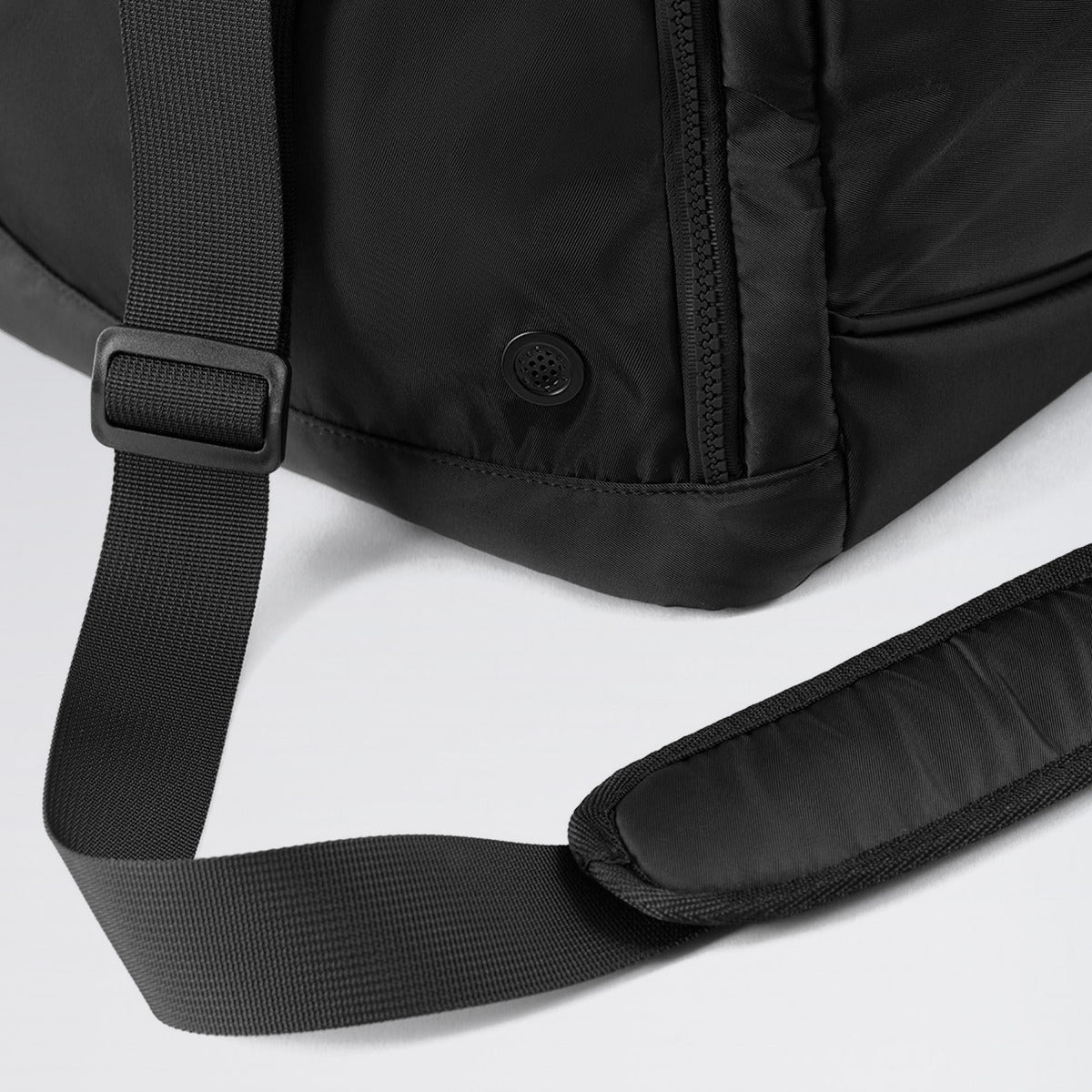 Close-up of a black backpack with a strap on a light gray background