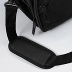 Black backpack with a shoulder strap on a light gray background