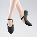 Black ballet shoes worn by a person on a light gray background