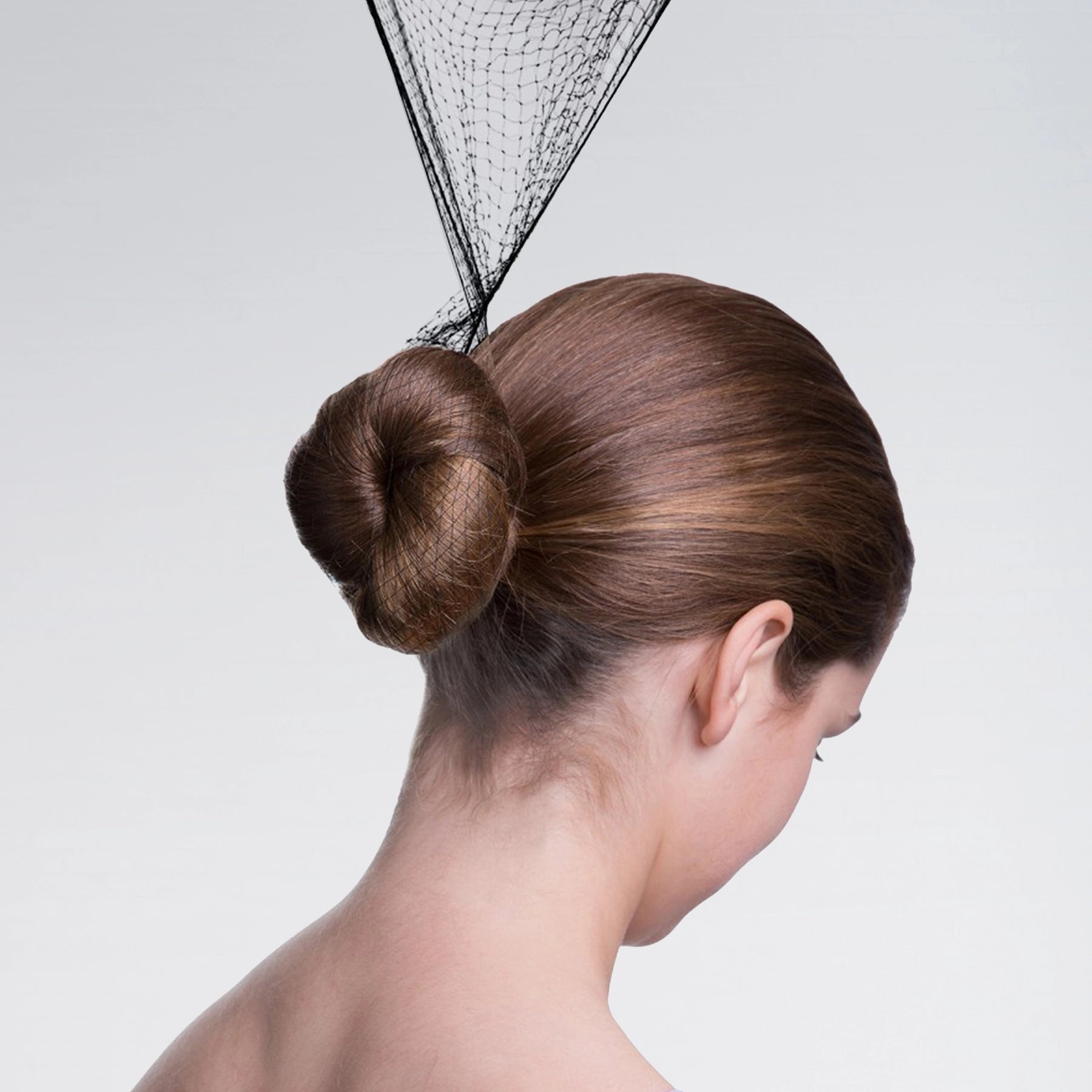 Woman with a stylish hair bun and decorative headpiece on a plain background