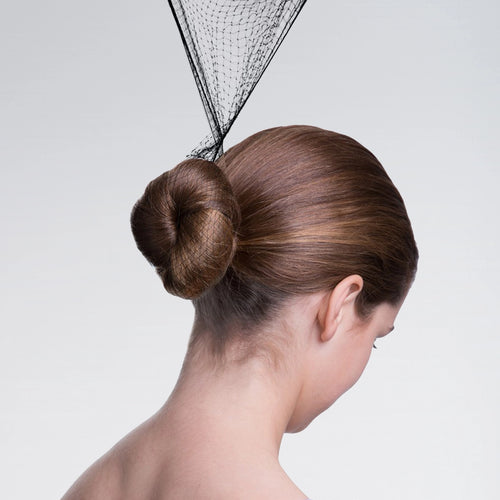 Woman with a stylish hair bun and decorative headpiece on a plain background