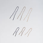 Set of black and gold hairpins on a light gray background