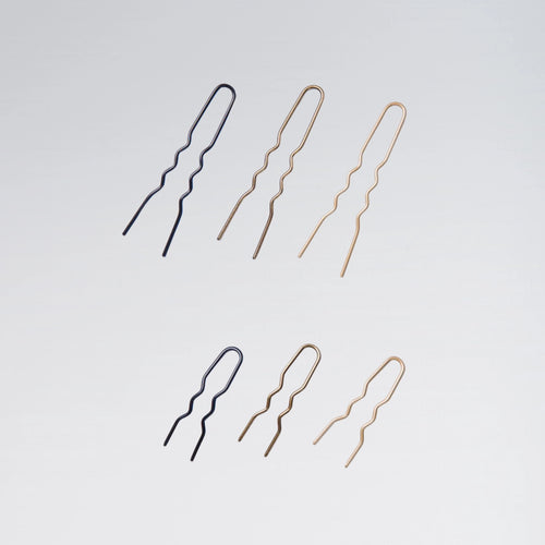 Set of black and gold hairpins on a light gray background