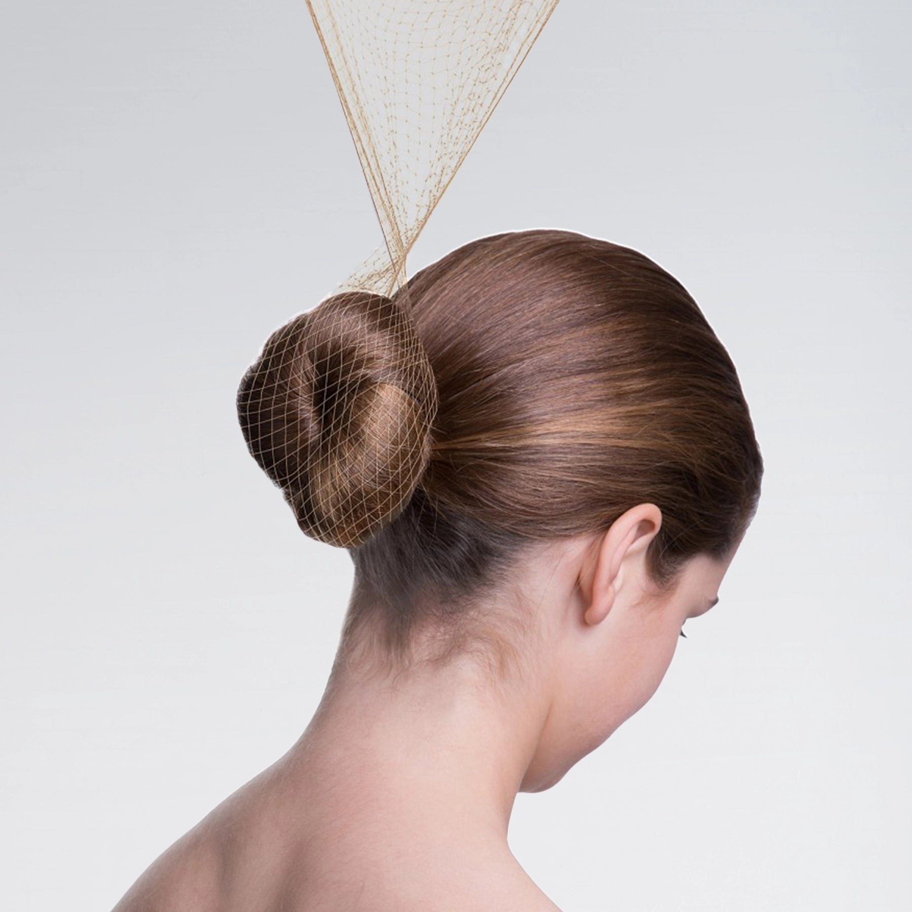 Woman with a stylish hair bun wearing a decorative headpiece on a plain background