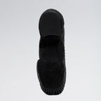 Black slip-on shoe with textured sole on a light gray background