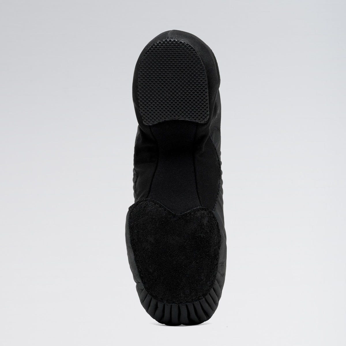 Black slip-on shoe with textured sole on a light gray background
