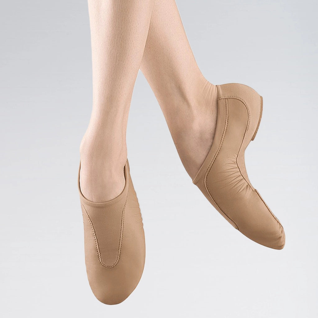 Beige ballet shoes worn by a person on a light gray background