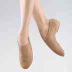 Beige ballet shoes worn by a person on a light gray background