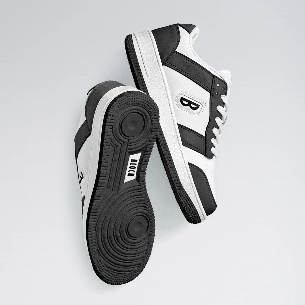 Black and white sneakers with a brand logo on a light gray background
