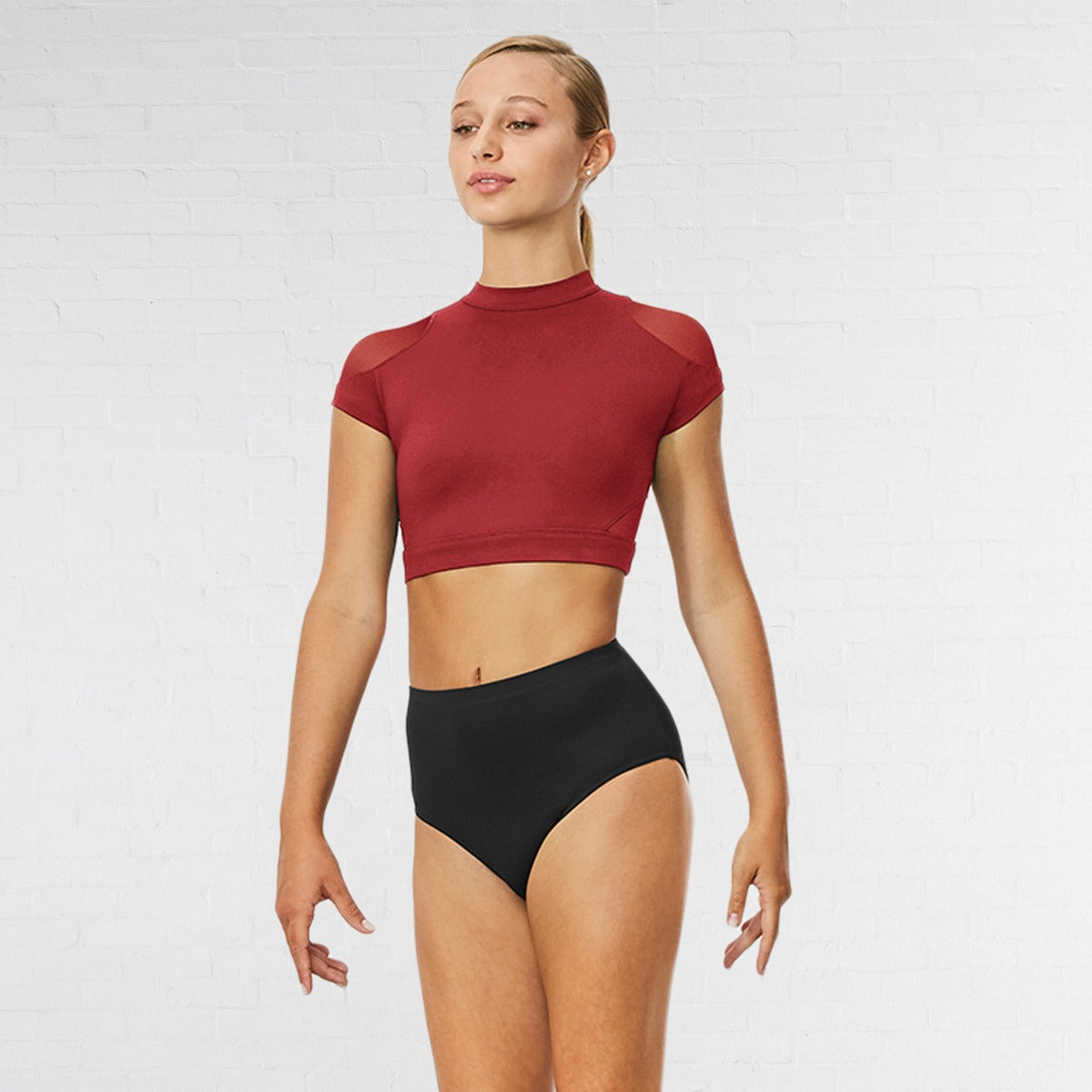 Woman wearing a red crop top and black high-waisted shorts on a white background