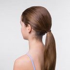Woman with long brown hair in a ponytail against a plain background