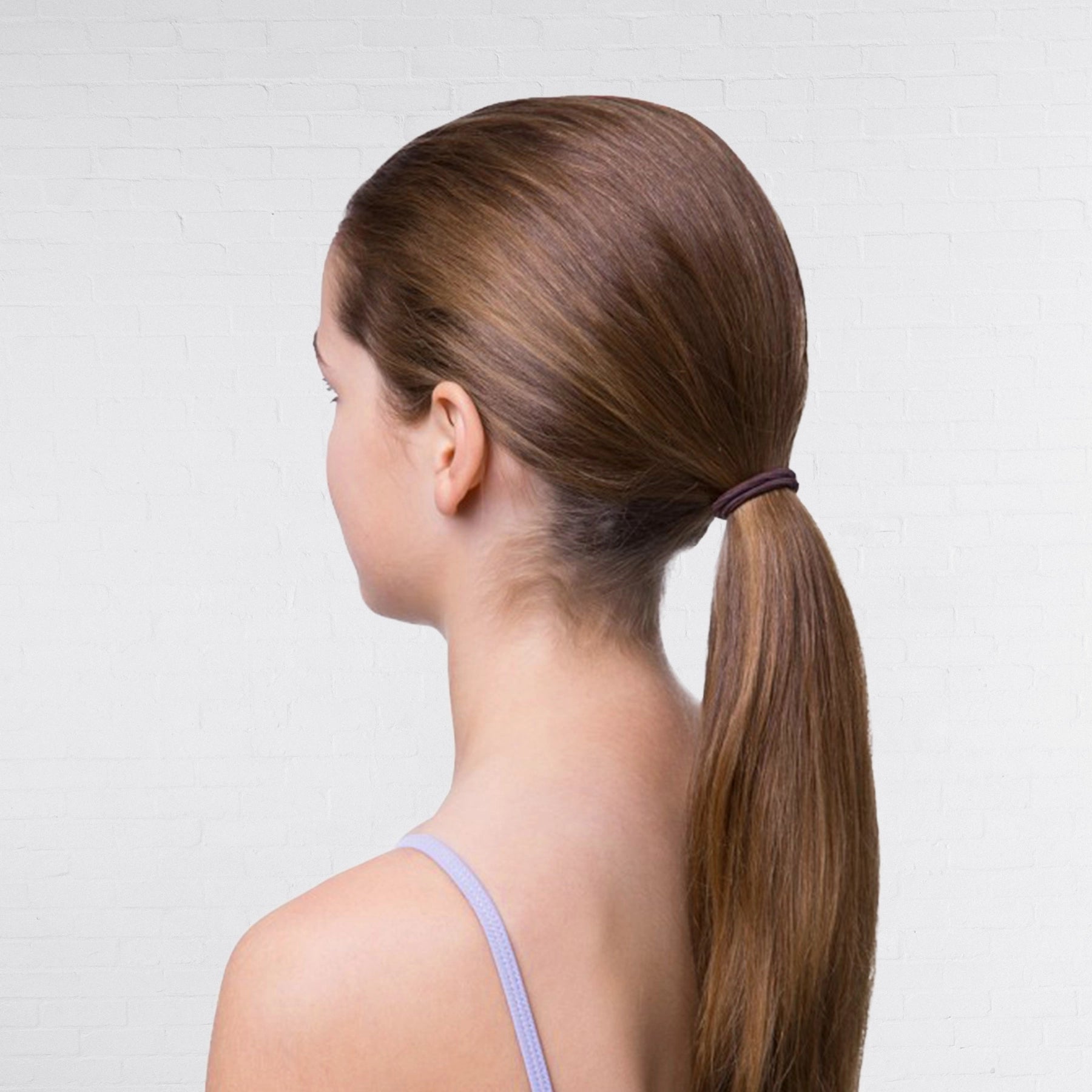 Woman with long brown hair in a ponytail against a plain background