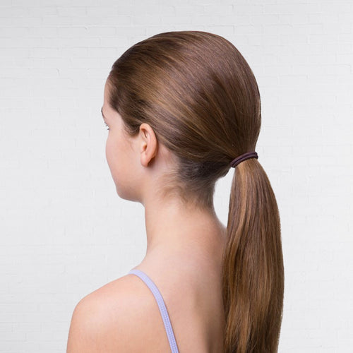Woman with long brown hair in a ponytail against a plain background