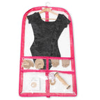 Clear garment bag with pink trim containing a black dress, shoes, and accessories on a white background