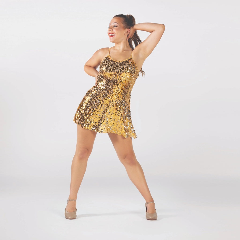 A woman modeling a short, sleeveless gold sequin dress with thin straps, posing against a light gray studio background.