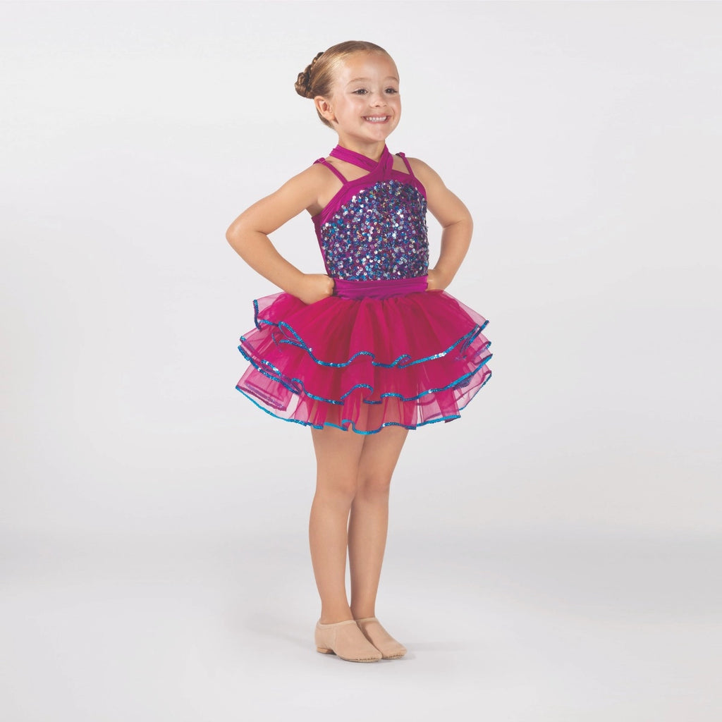 Young dancer wearing a raspberry pink sequin tutu costume by 1st Position featuring a crossover halterneck design, sparkling sequin bodice and layered tutu skirt with blue glitter trim.