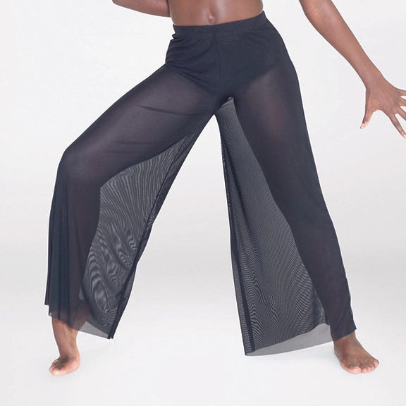 Woman wearing a pink top and black pants with sheer panels on a white background