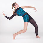 A young gymnast in a black and teal patterned leotard poses dynamically on a seamless light gray studio background.