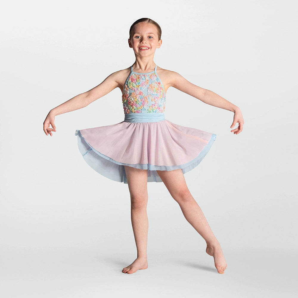 A young girl dancer posing in a sleeveless halter leotard with a pastel floral bodice, a light blue waistband, and a layered light pink and blue tutu skirt, set against a solid light gray background.