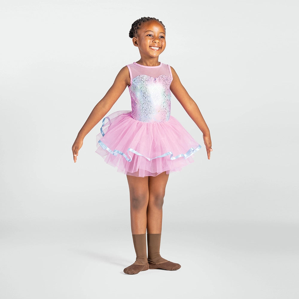 A young girl dancer wearing a pink tutu ballet dress with a sequined bodice, posed against a light gray studio background.