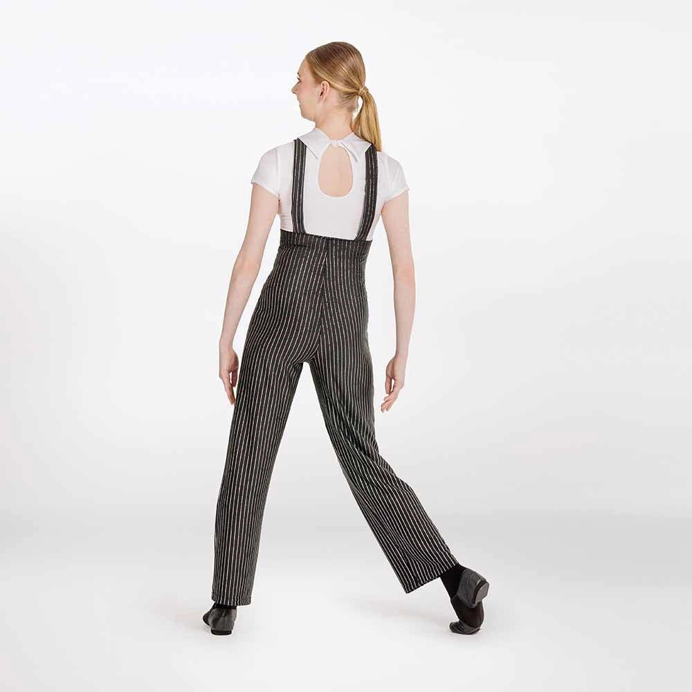 A woman modeling a pair of black and white vertically striped pinstripe suspender pants, shown from a rear three-quarter view against a plain white studio background.