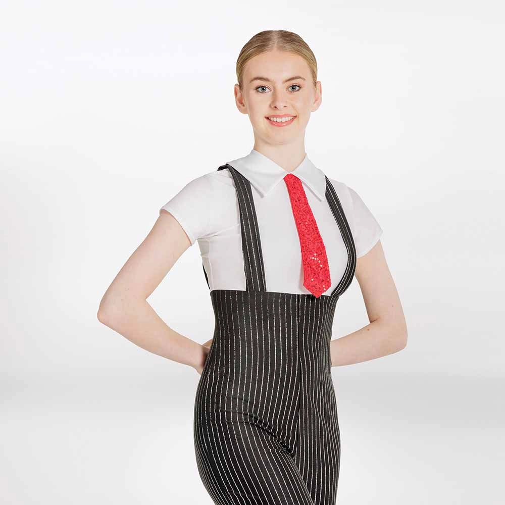 A woman modeling a black and white pinstriped jumpsuit with shoulder straps, styled over a white short-sleeve collared shirt and a red patterned necktie, against a plain white studio background.