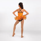 A young girl dancer is shown from behind wearing an orange and black leotard with a ruffled tutu skirt, standing on a light gray studio background.