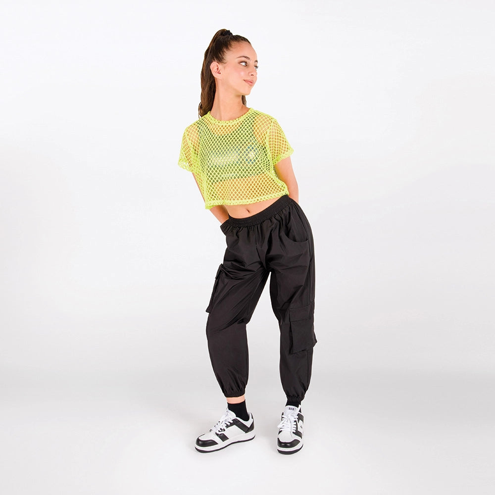A woman modeling a neon yellow-green cropped mesh top and black cargo jogger pants against a plain white studio background.