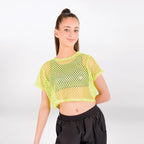 A young woman modeling a neon yellow-green short-sleeve mesh crop top with black pants against a light gray studio background.