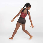 Dancer in a red sequin top and brown shorts on a white background