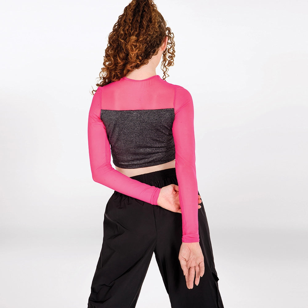 A model shown from the back wearing a long-sleeve crop top with a bright pink mesh upper section and a textured dark gray lower section, paired with black pants, against a light gray studio background.