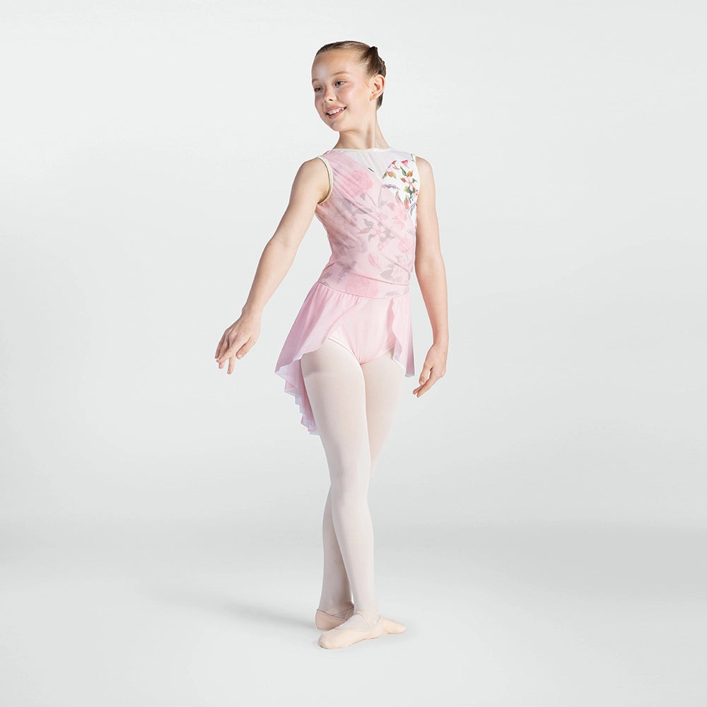 A young girl dancer wearing a light pink sleeveless leotard with a floral print on the back, a matching pink tutu, and light pink tights, posing against a light gray studio background.