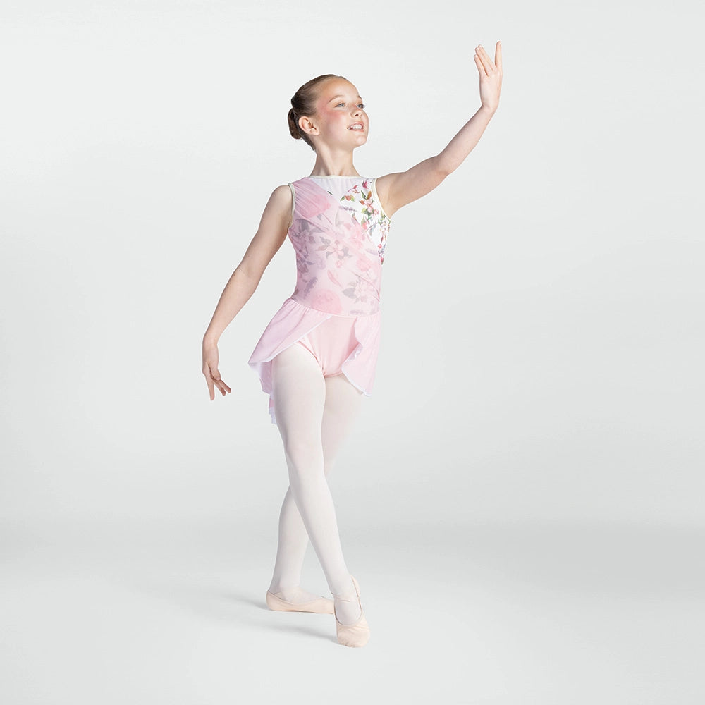 A young girl dancer posing in a light pink sleeveless leotard with floral embroidery, white tights, and ballet slippers against a light gray studio background.
