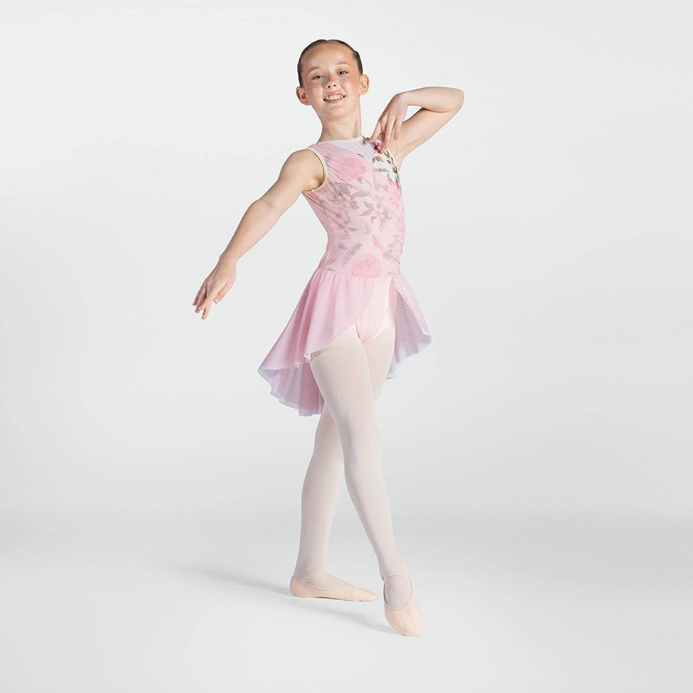 A young ballerina girl posing in a light pink sleeveless leotard with a floral pattern, sheer pink tutu skirt, and light pink tights against a light gray studio background.