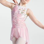 A child wearing a sleeveless pink leotard with a floral print on the bodice and a sheer pink ruffled skirt, posed against a light gray studio background.