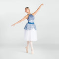 A woman in a blue and white ballet leotard and tulle skirt poses in a ballet position on pointe against a light gray studio background.