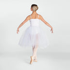 A young ballerina viewed from behind, wearing a white spaghetti-strap tutu dress with a full tulle skirt and pink pointe shoes, posed against a light gray studio background.