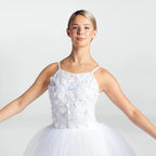 A young ballerina wearing a white sleeveless tutu dress with a textured, floral applique bodice and a full tulle skirt, posed against a light gray studio background.